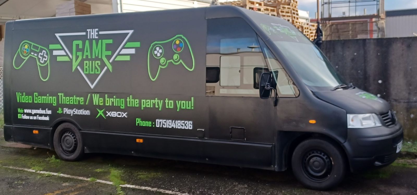 The Game Bus mobile gaming bus parked, side view with green branding